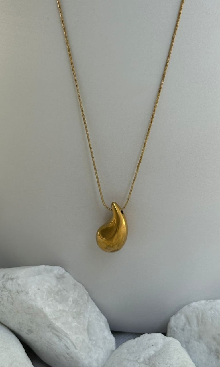 Gold necklace with a pendant on a light gray background
