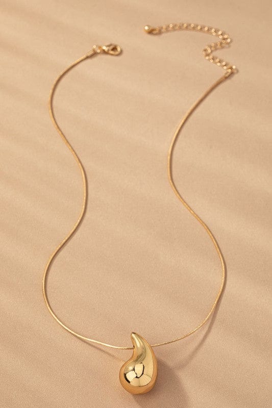 Gold necklace with a teardrop-shaped pendant on a beige background